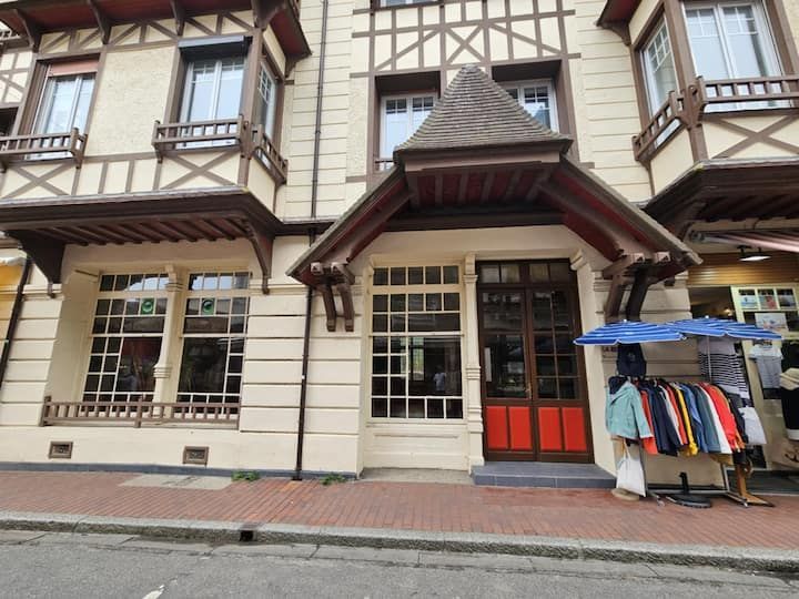 Façade d'immeuble de style Tudor, entrée de magasin, porte rouge, portant à vêtements et trottoir.