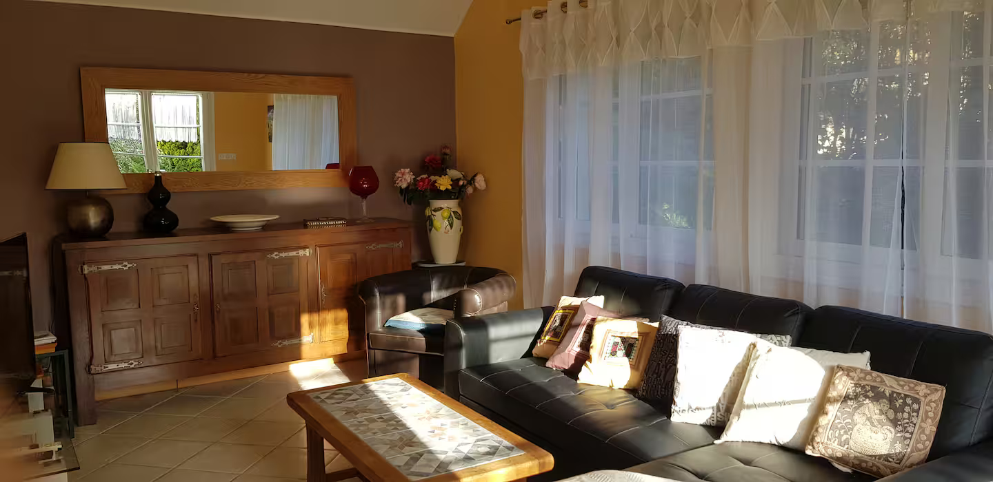 Un salon avec un canapé, une table, un miroir et une commode.