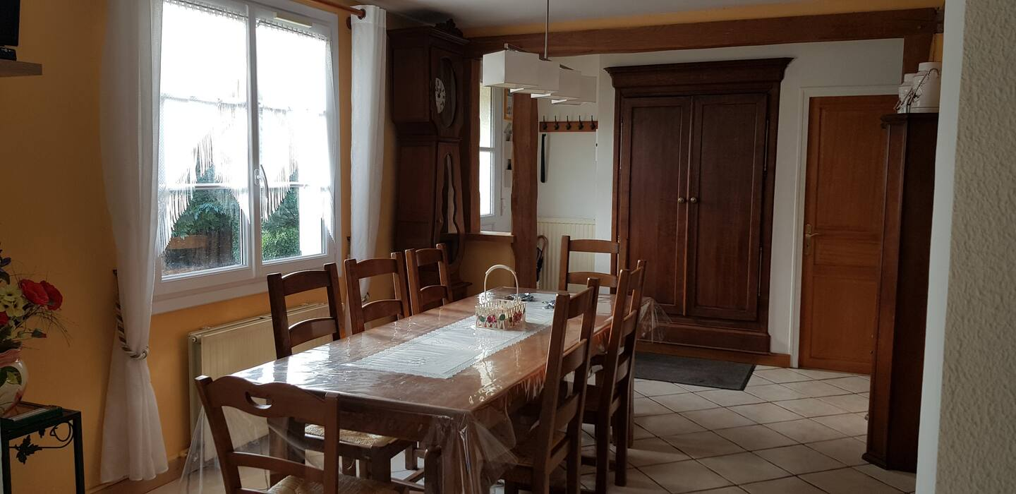 Une salle à manger avec une longue table et des chaises dans une maison.