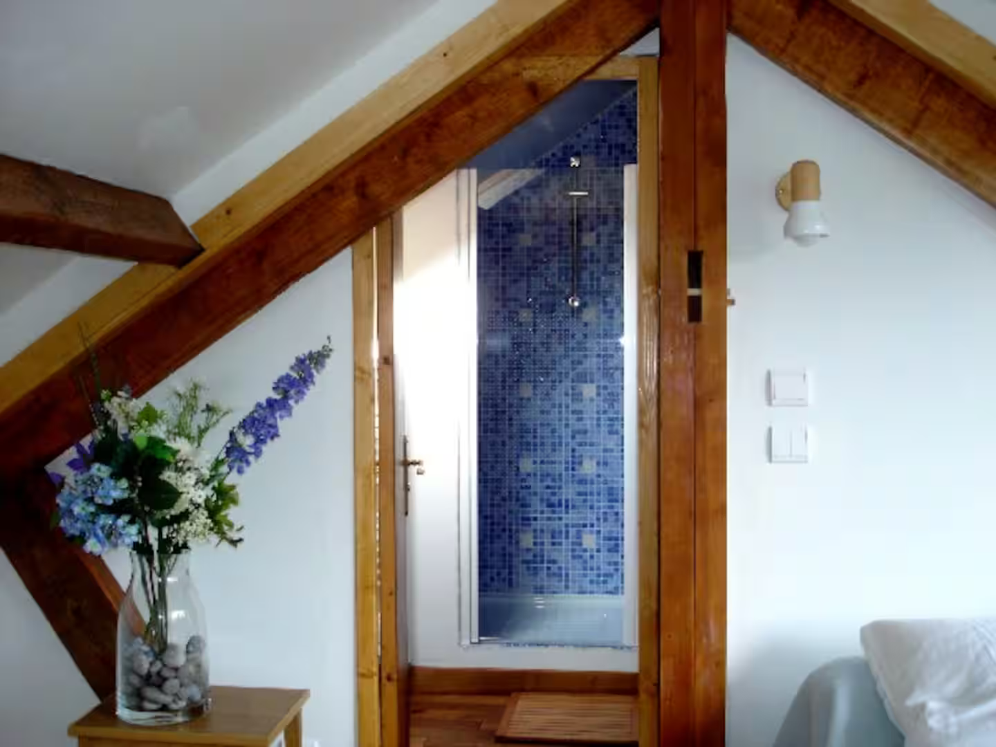 Une chambre avec un lit et un vase de fleurs