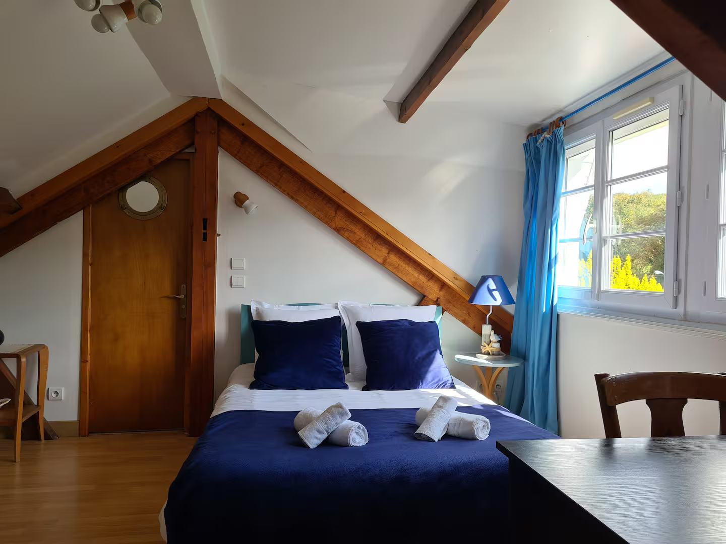 Une chambre avec un lit, une table, des chaises et une fenêtre.