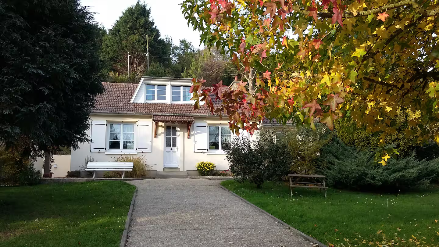 Une maison avec une allée de gravier qui y mène est entourée d'arbres et d'herbe.