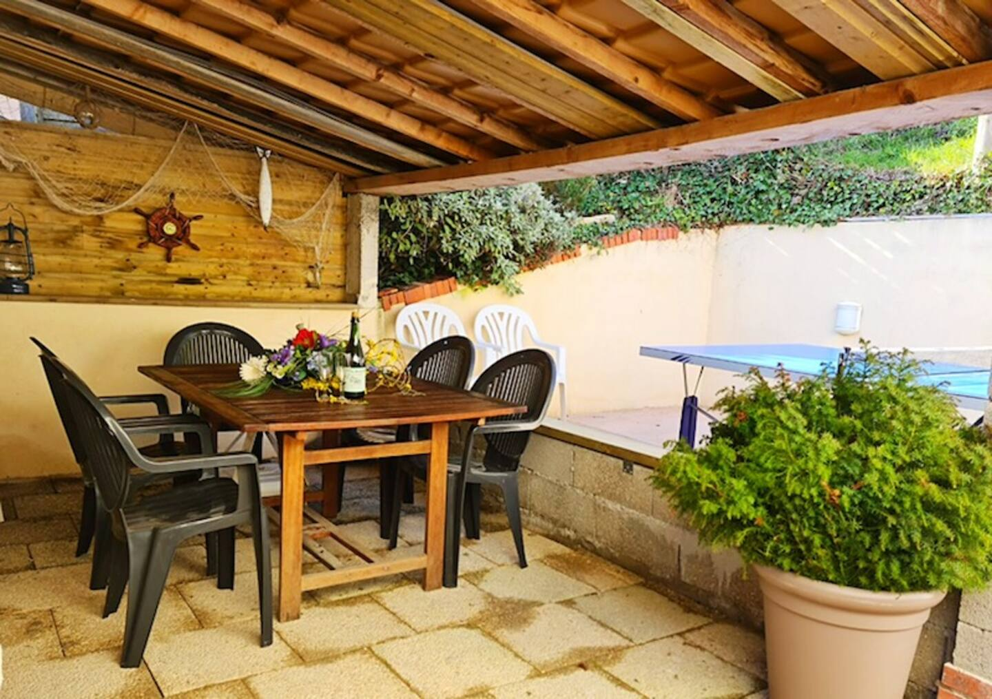 Un patio avec une table et des chaises sous un toit en bois.