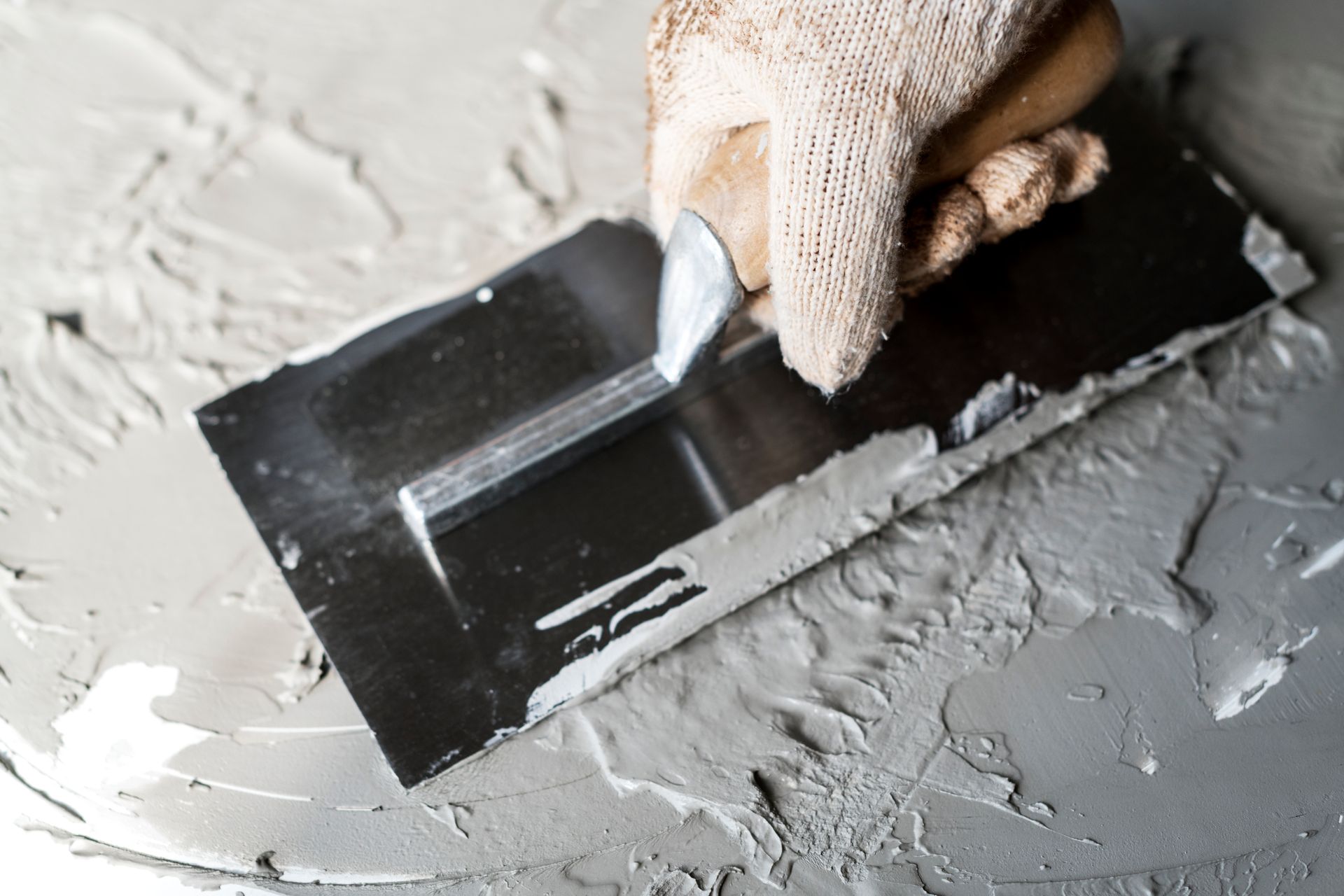 A person is plastering a wall with a trowel.
