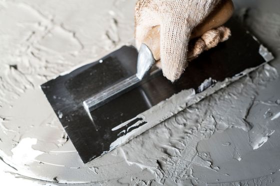 A person is plastering a wall with a trowel.