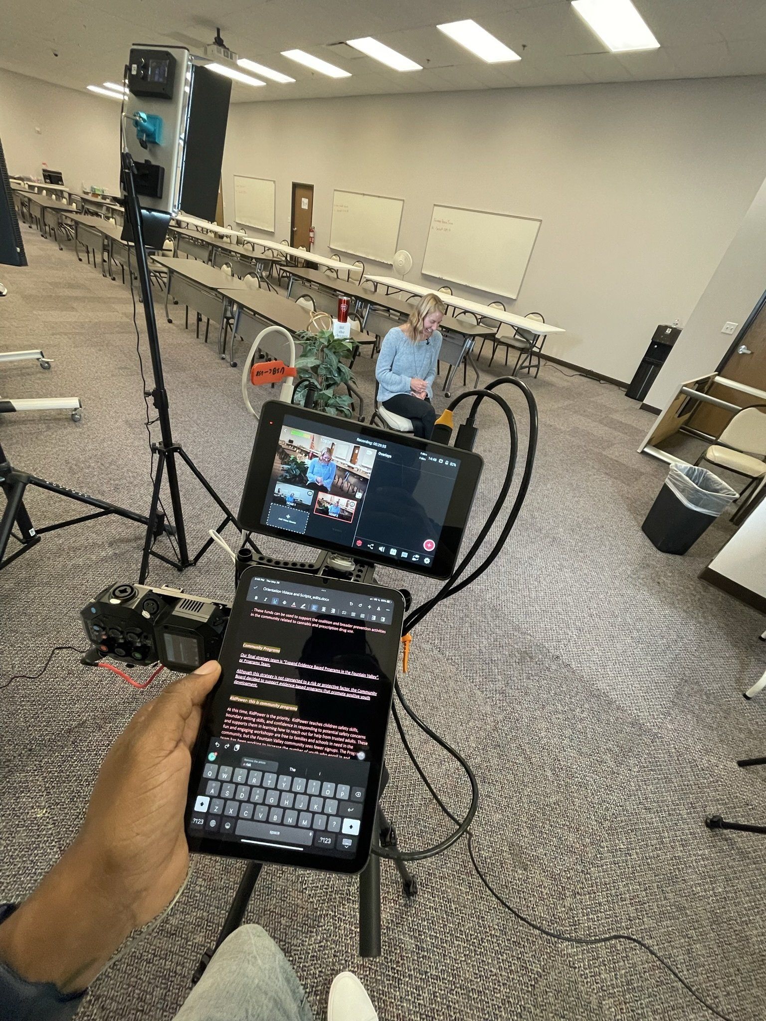 A person is holding a tablet in front of a camera in a room.