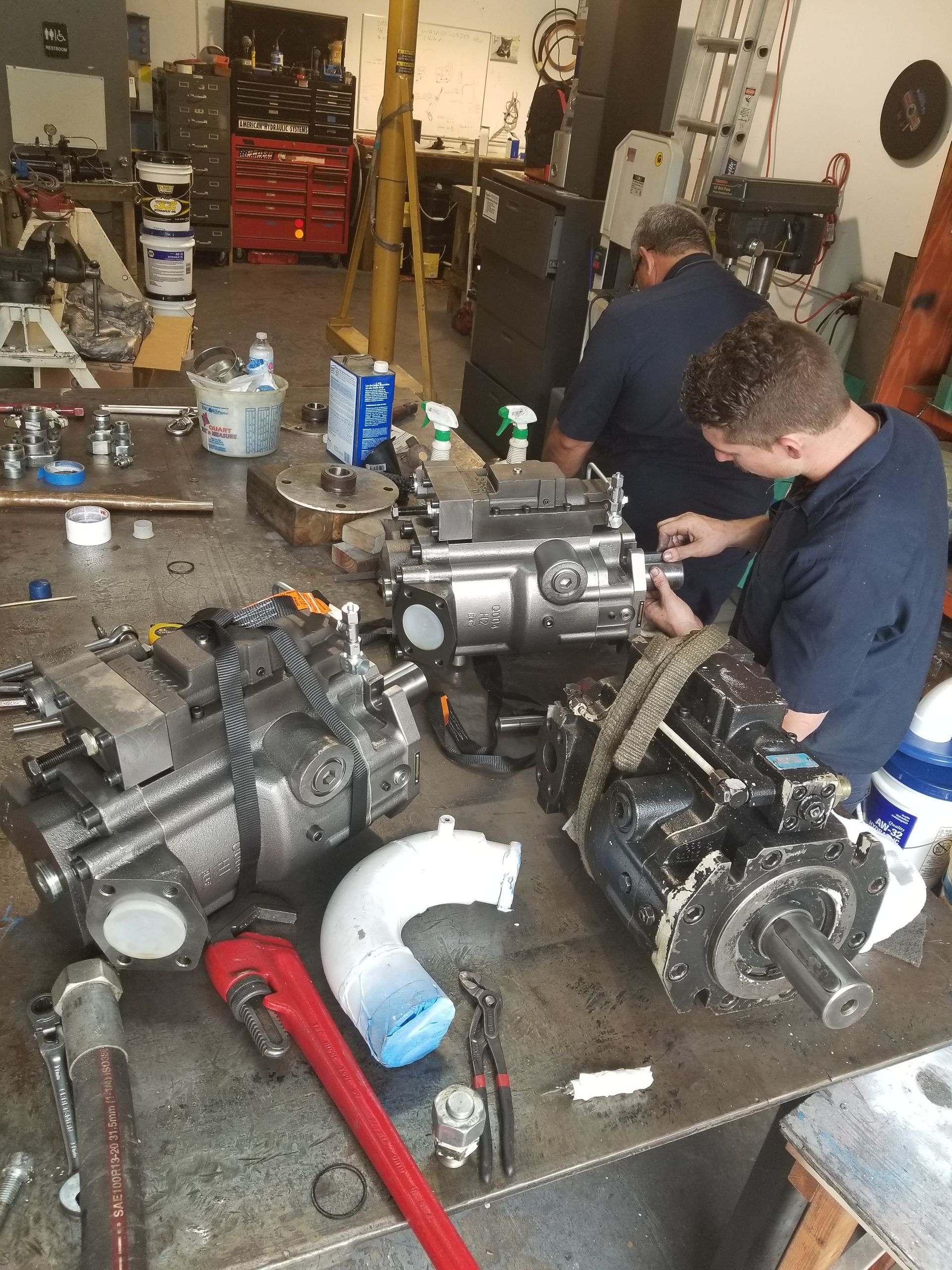 Two men are working on a machine in a garage.