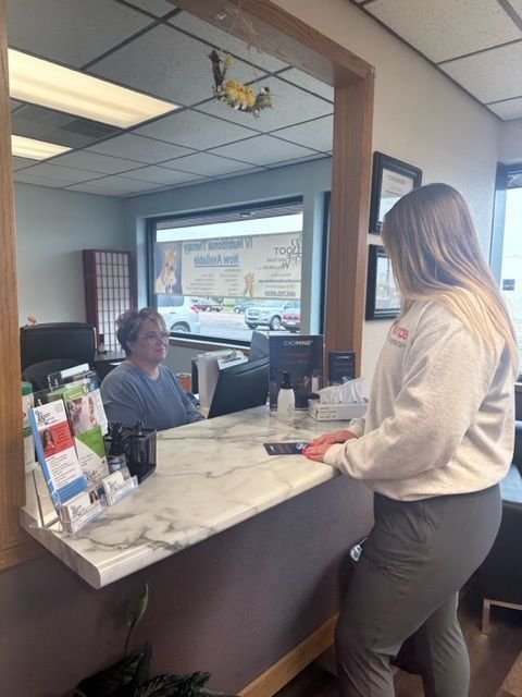 Woman at a desk with a receptionist, in an office setting.