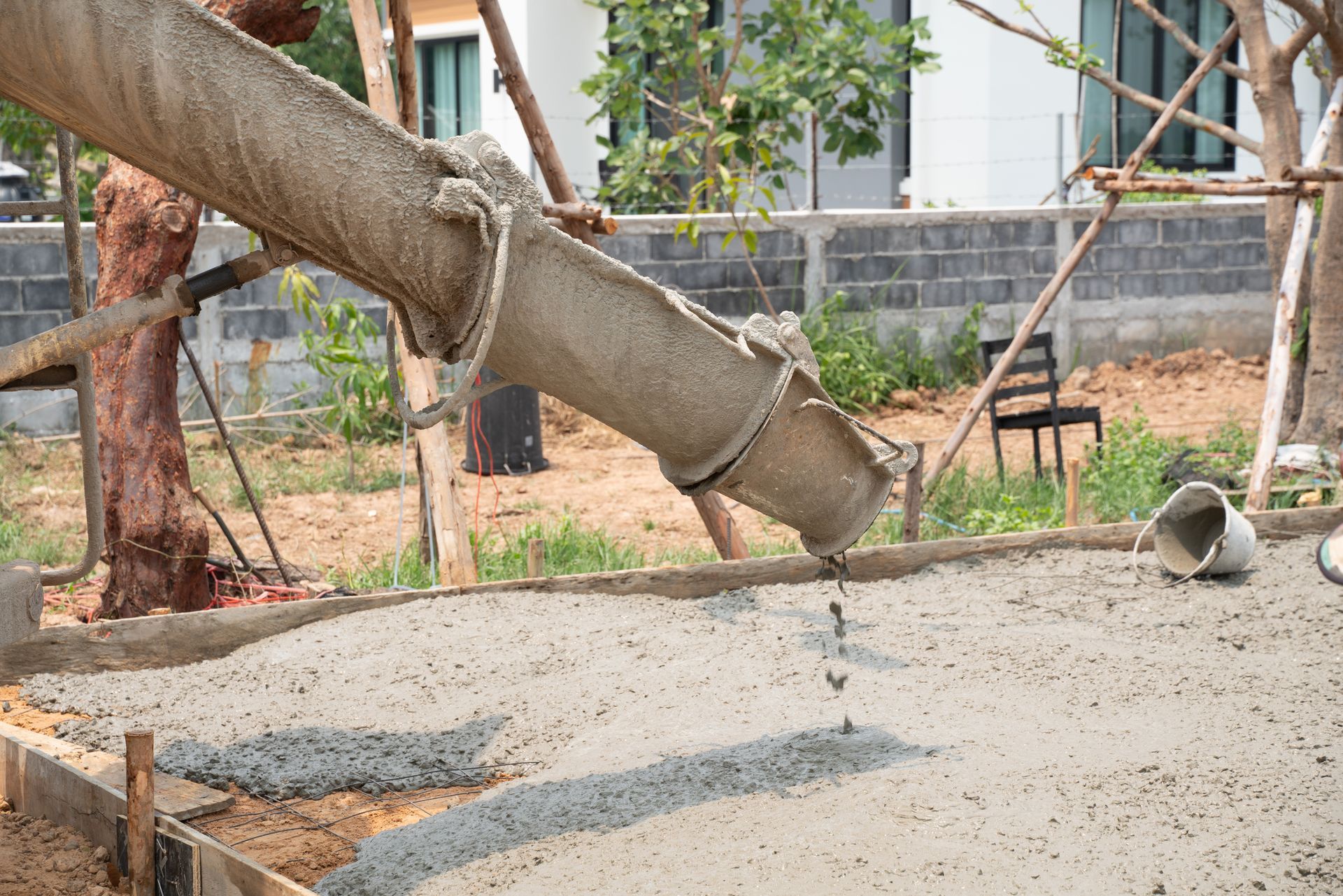 Concrete being poured from a chute into a wooden frame at a construction site.