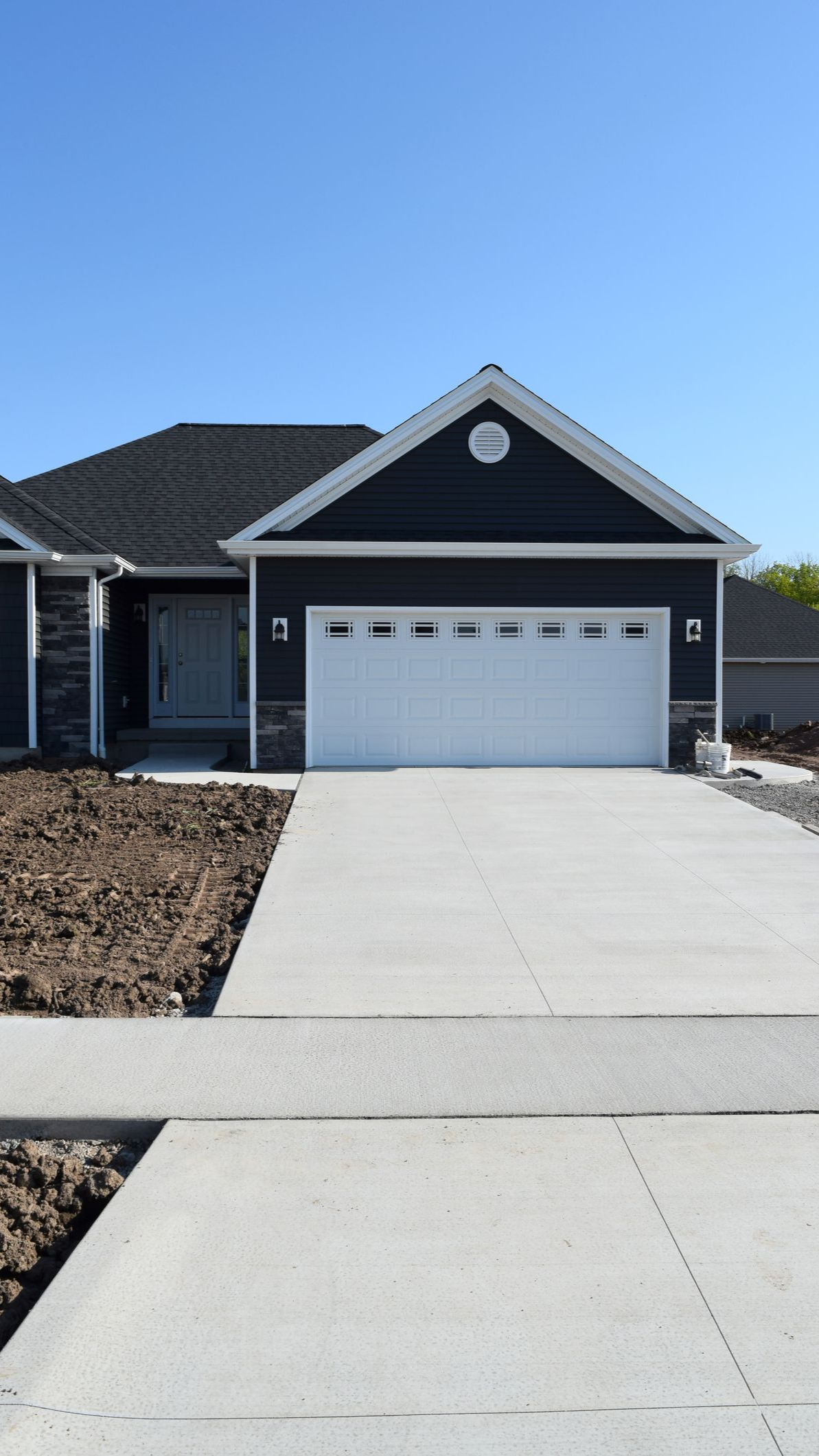 Blue-sided house with white garage door and concrete driveway on a sunny day. Blue-sided house with white garage door and concrete driveway on a sunny day.