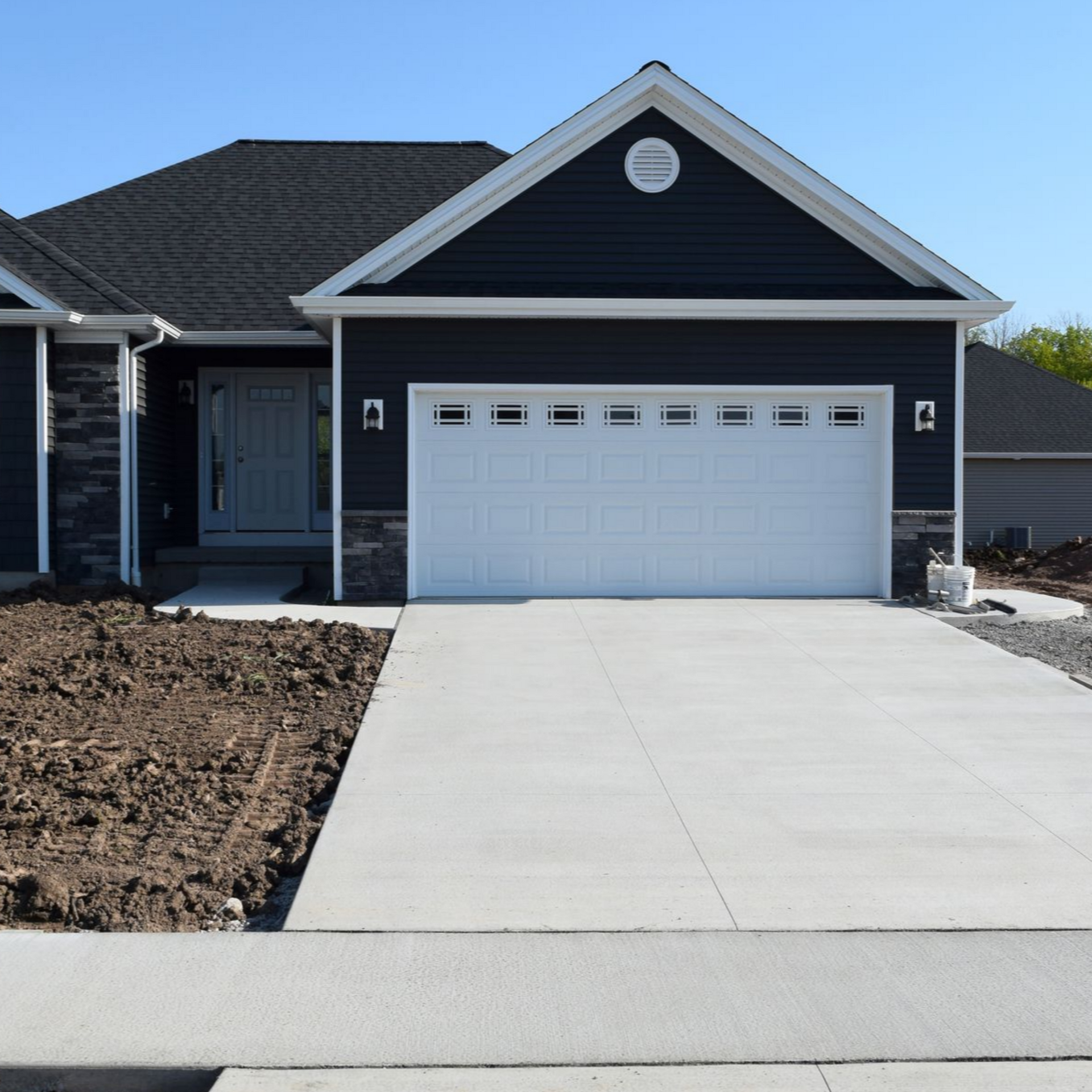Blue-sided house with white garage door and concrete driveway on a sunny day. Blue-sided house with white garage door and concrete driveway on a sunny day.