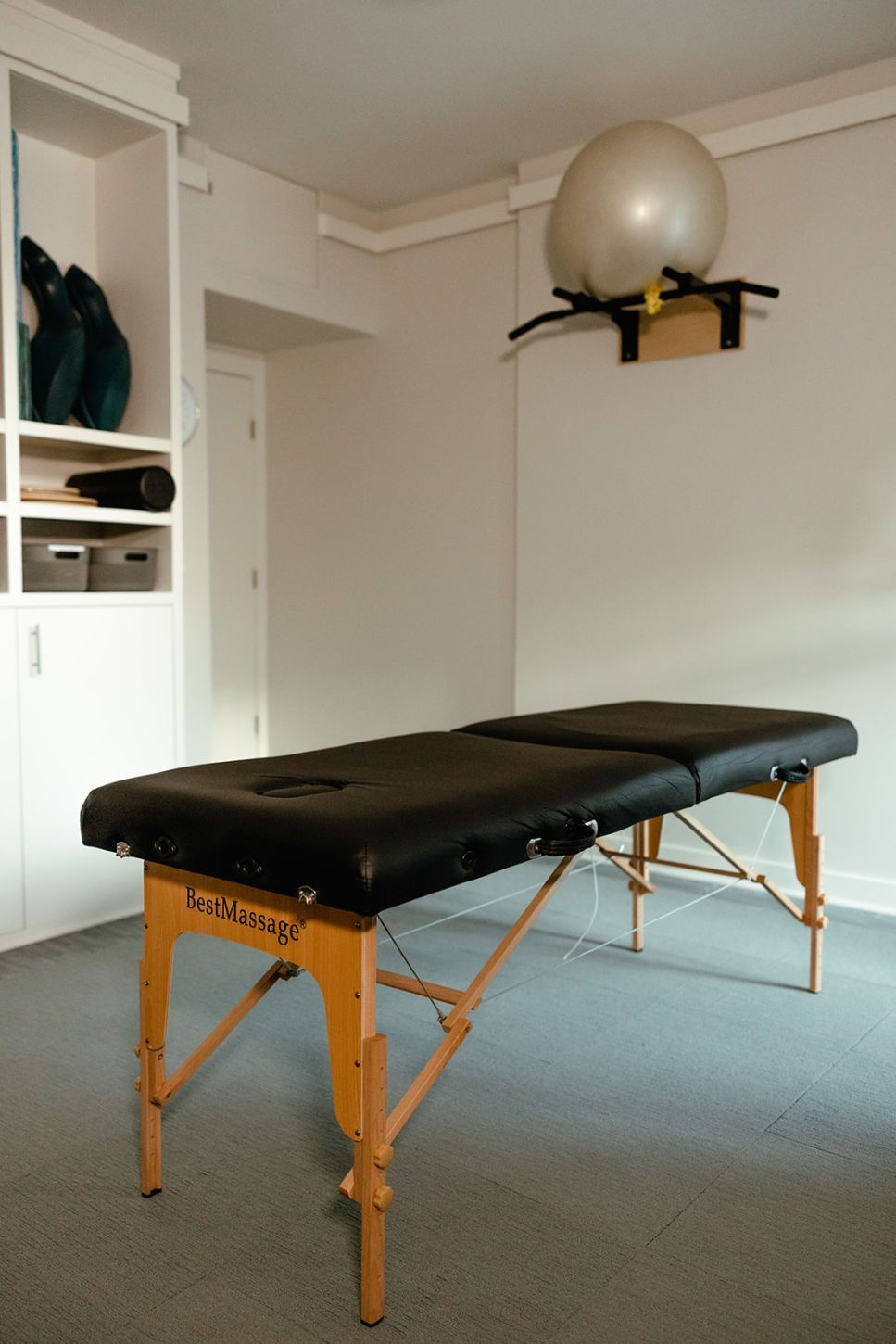 A massage table in a room with a pilates ball on the wall