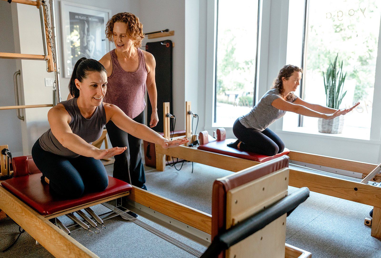Two women are doing pilates on a pilates reformer