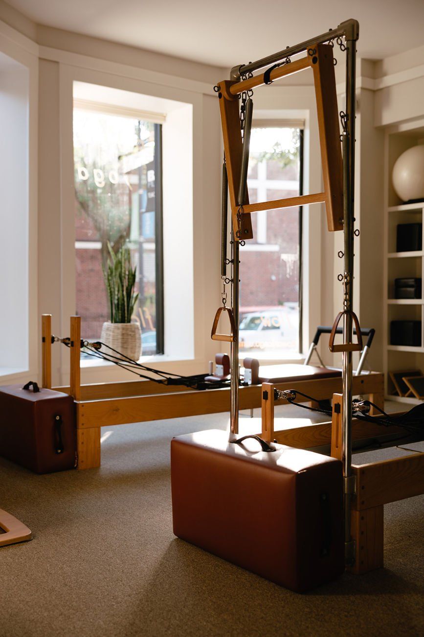 A pilates reformer is sitting in a room next to a window