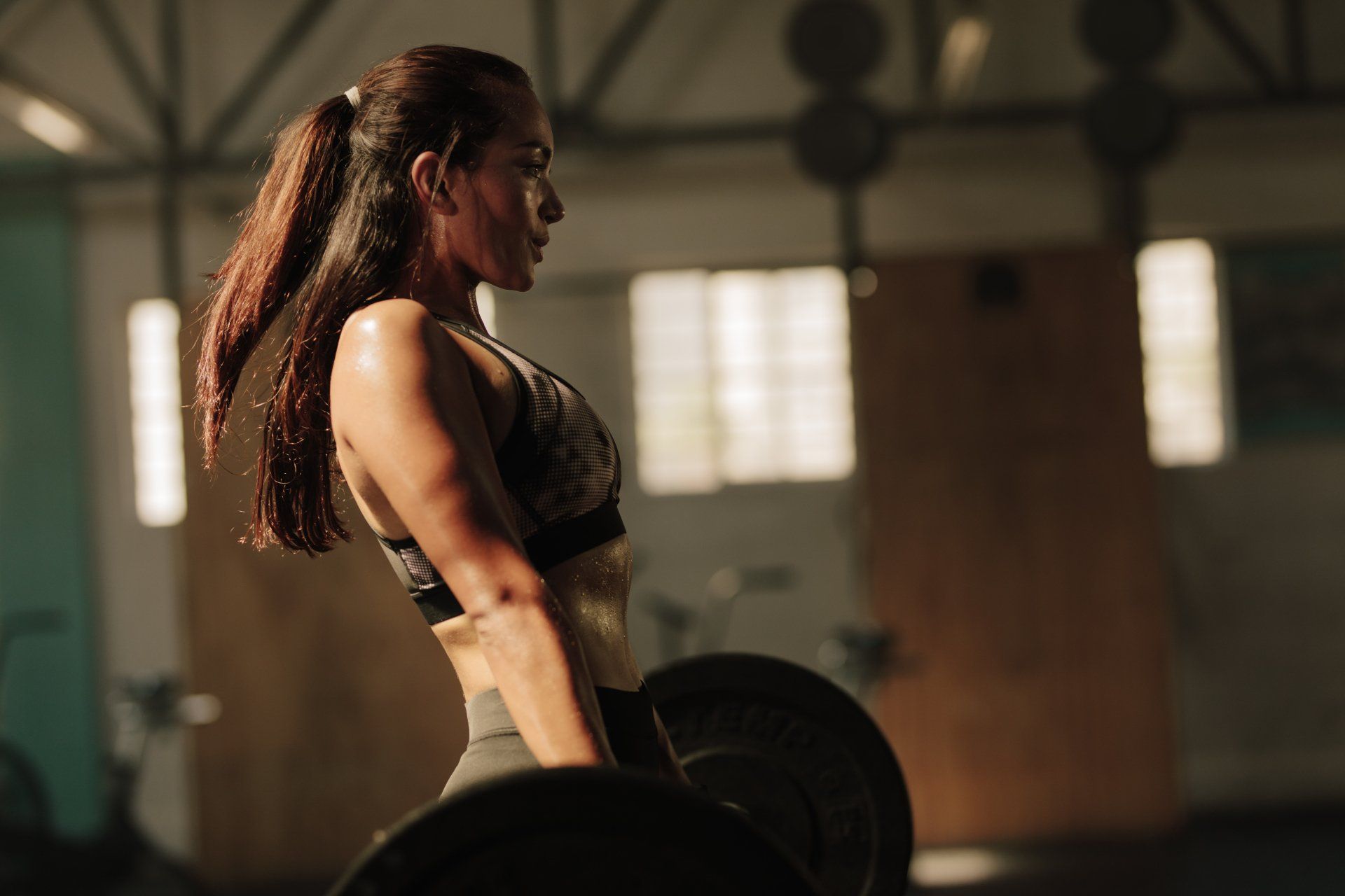 Physically fit woman lifting heavy weights. Fitness female doing heavy weight workout at gym.