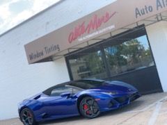 A blue lamborghini huracan is parked in front of a car dealership.