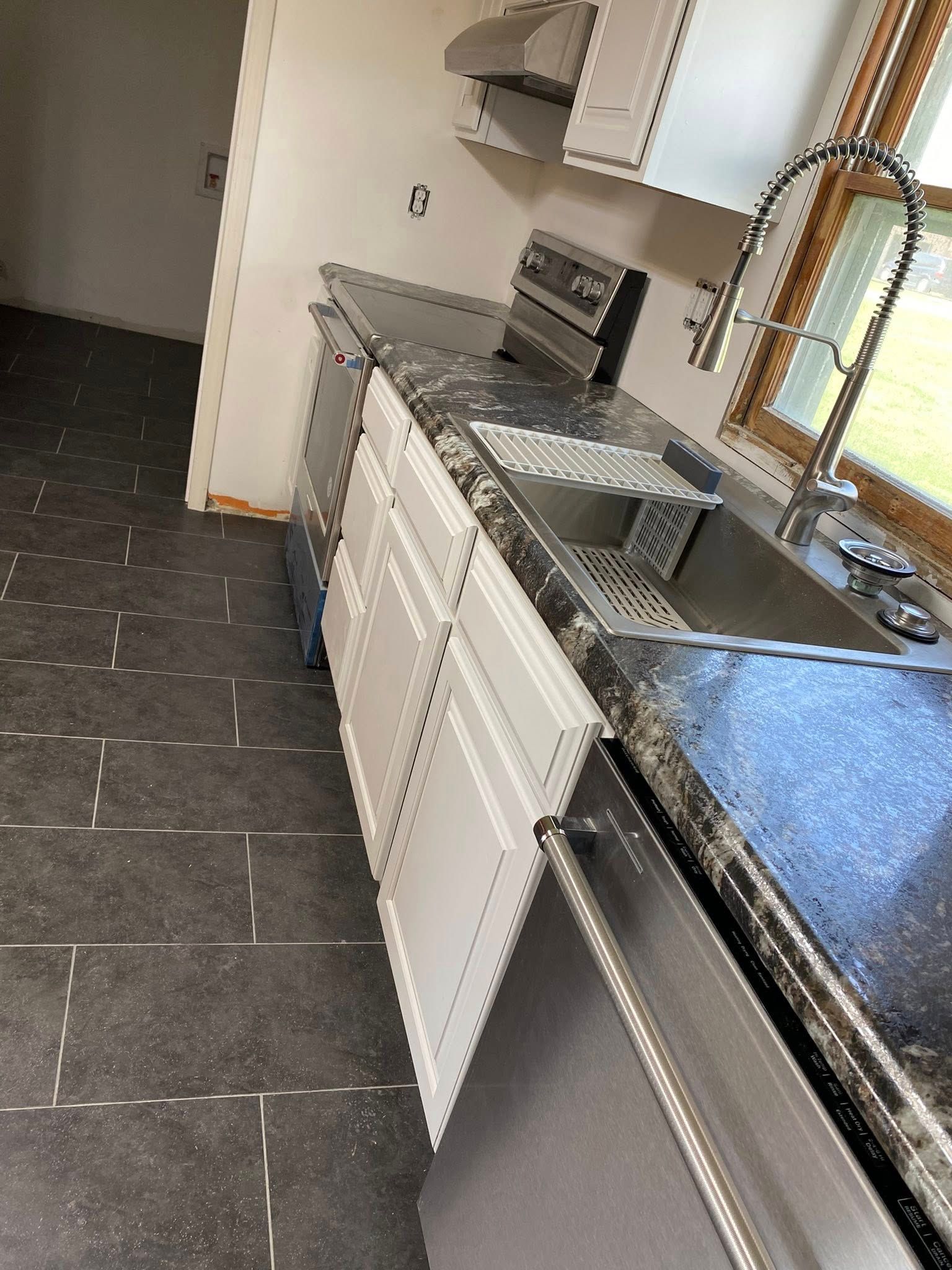 Kitchen with dark tile floor, white cabinets, and granite countertops along a wall