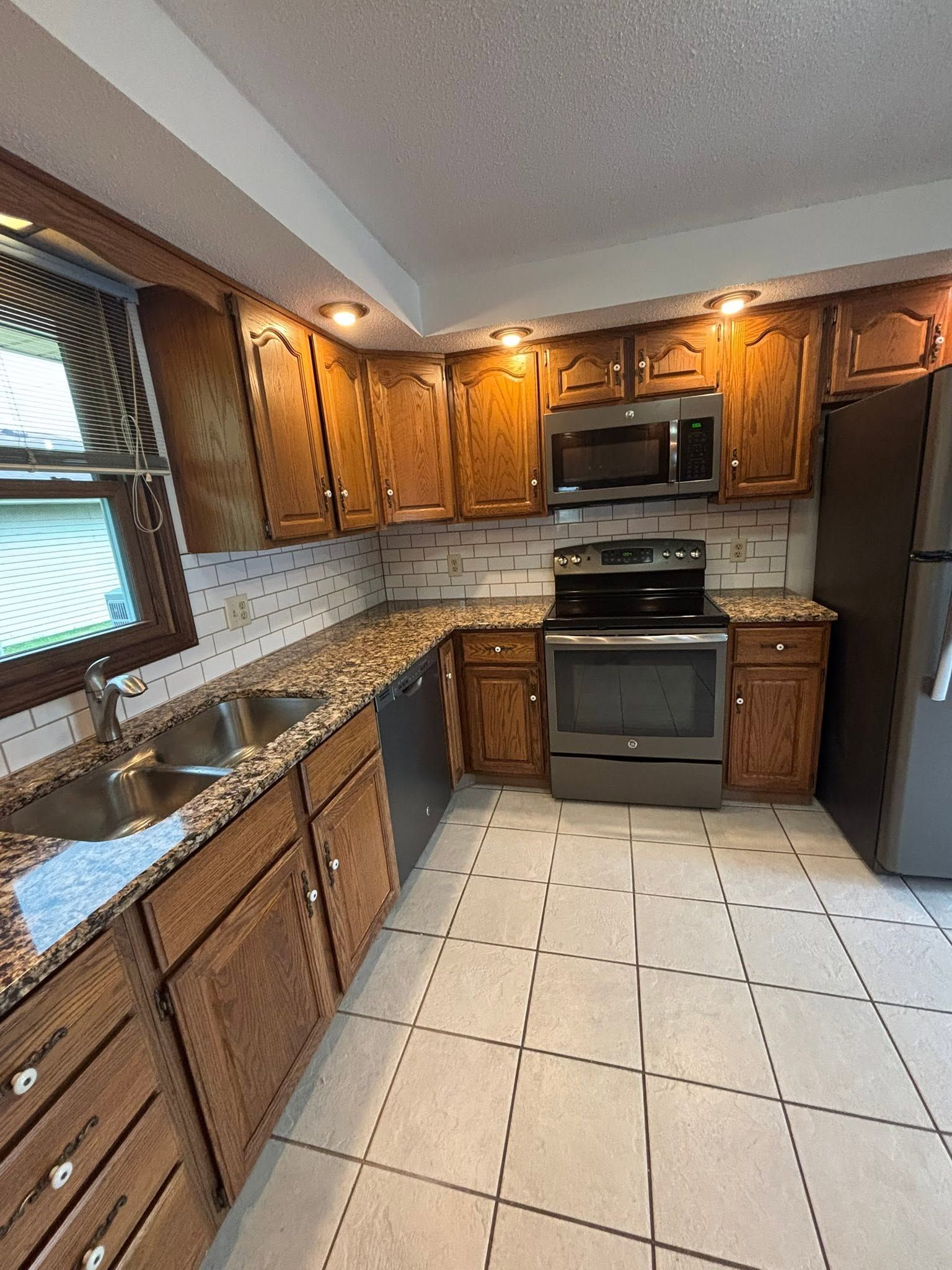 Small kitchen with a stainless steel stove and open cabinets above, white cabinets, and a granite-look countertop.