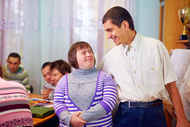 A man and a woman with down syndrome are standing next to each other in a room.
