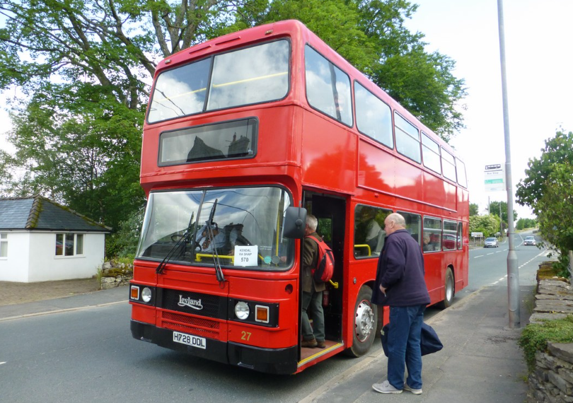 A red double decker bus is parked on the side of the road