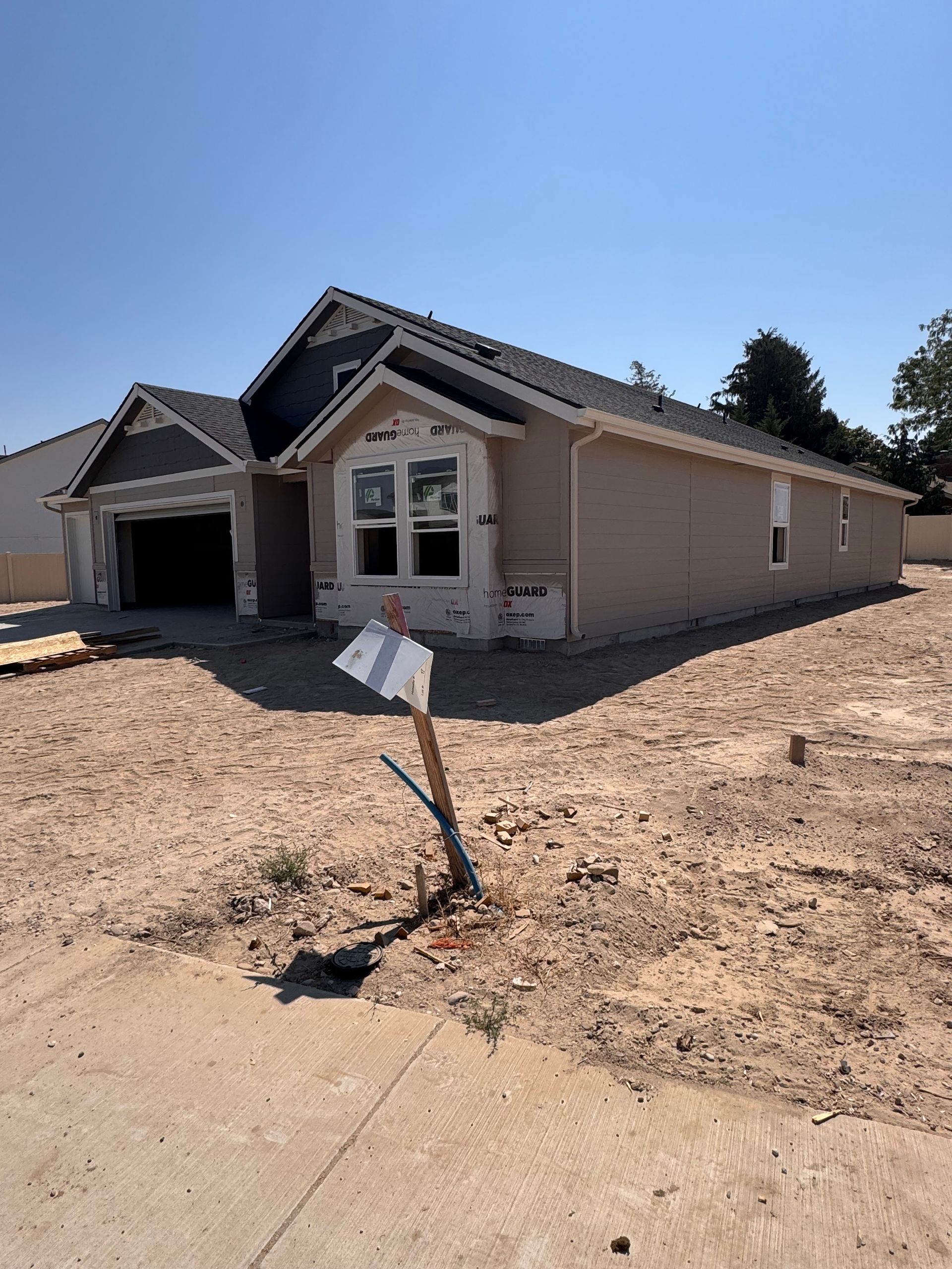 New house under construction with tan siding and a blue roof.
