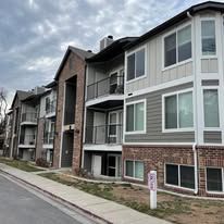 Apartment building with brick and siding under cloudy sky.