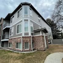 Exterior of a brick and stucco apartment building under a cloudy sky.