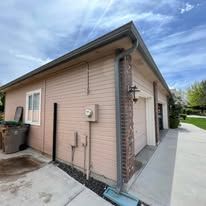 Exterior of a light pink house with a garage, cloudy sky in the background.