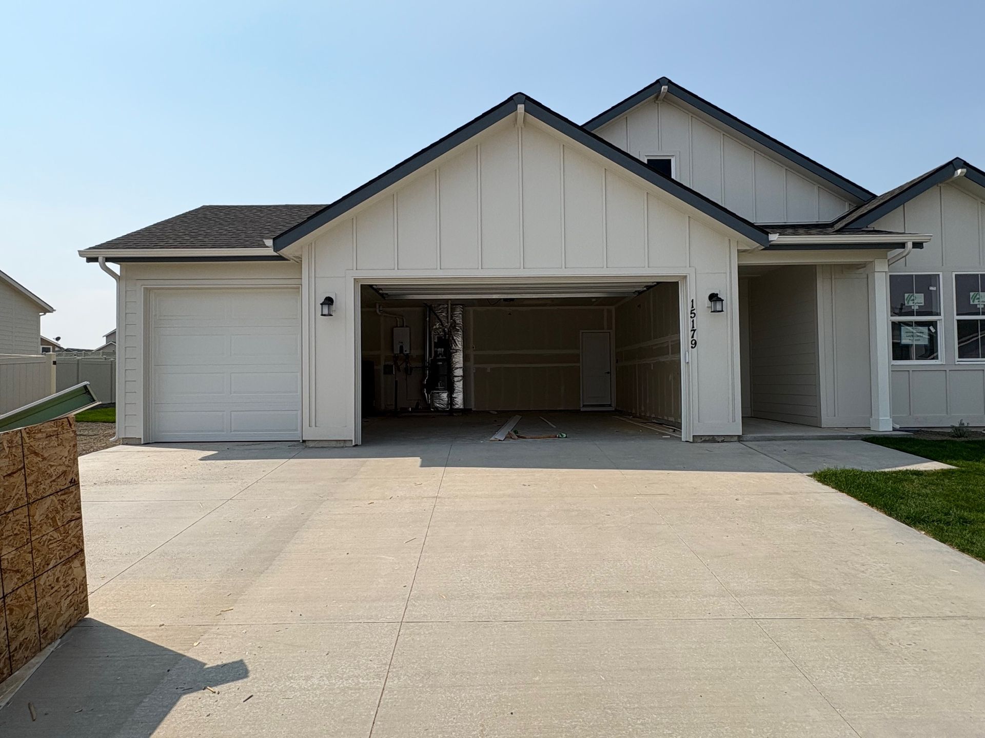 White house with open garage and driveway. Sunny outdoor setting.