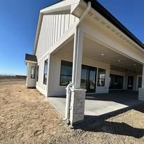 Exterior view of a new house with a covered patio and a stone-covered column.