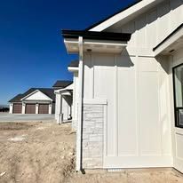 White house exterior with stone accent wall and black rain gutter.