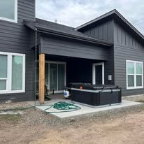Exterior of a house with a dark gray facade, covered patio, and a hot tub.