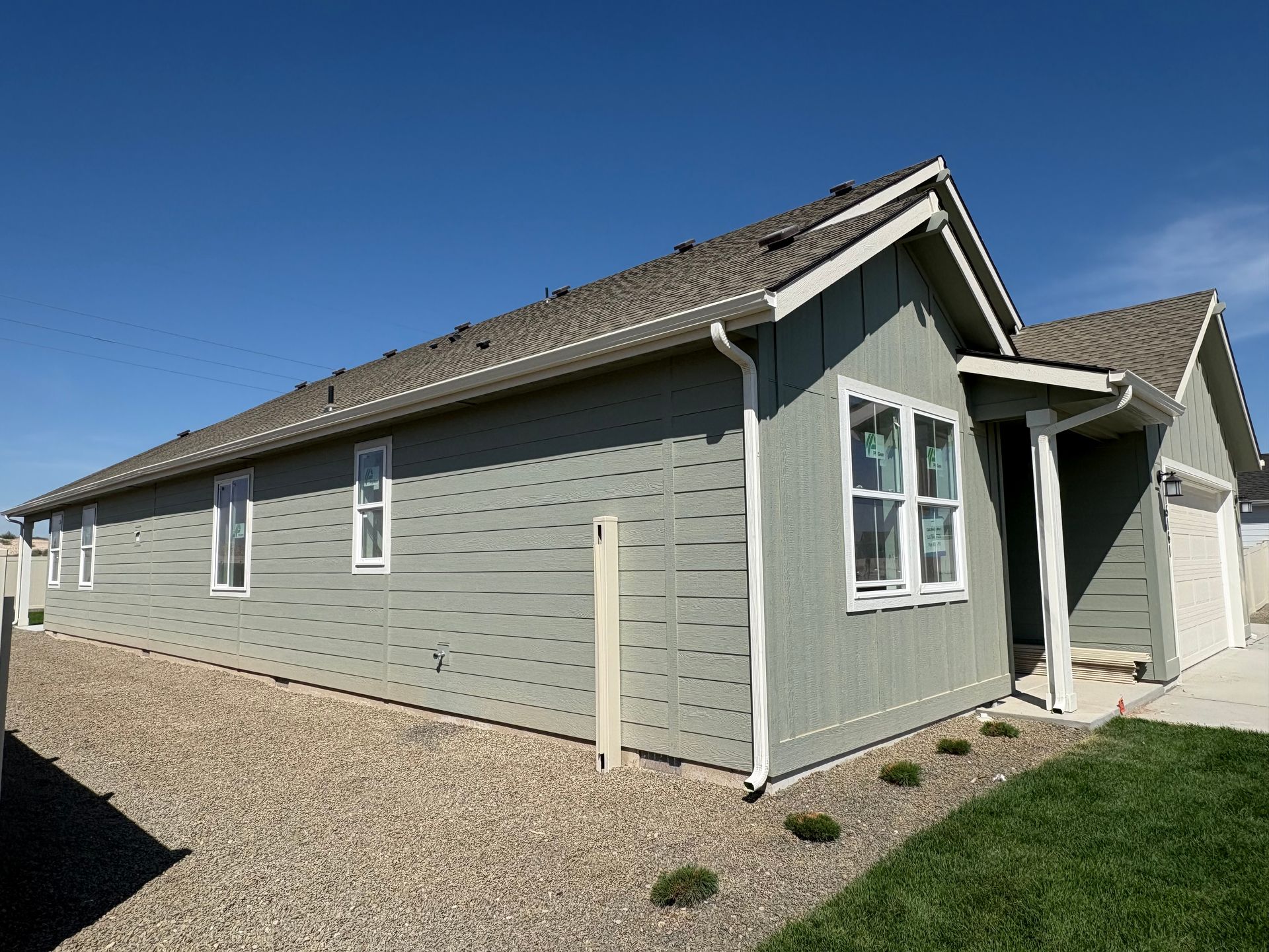 A light green house with white trim against a bright blue sky.