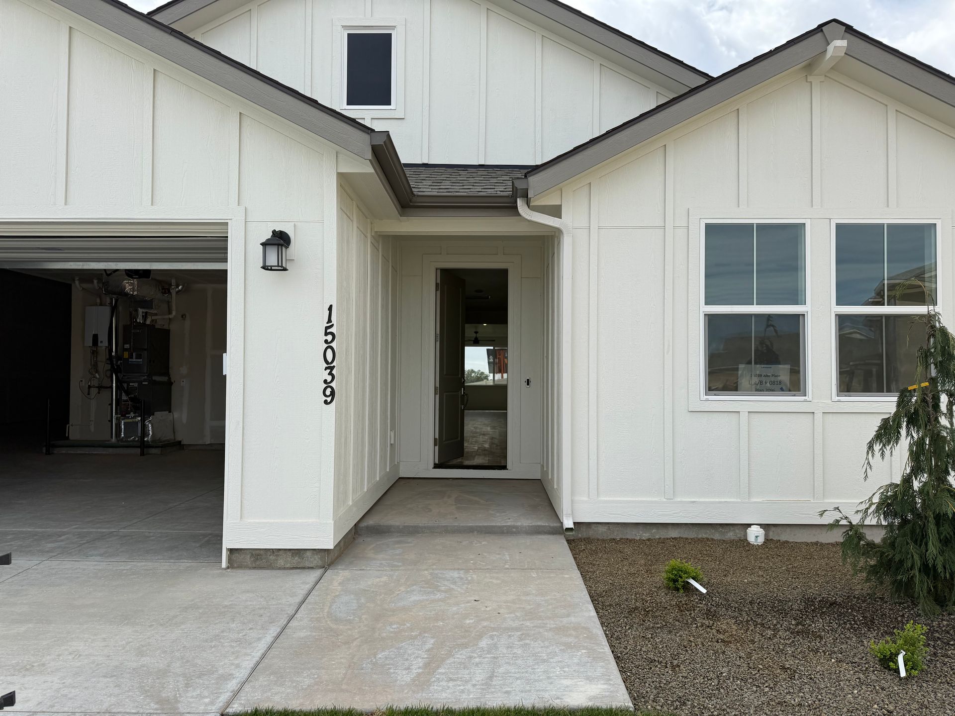 White house with a concrete walkway and garage. Black house numbers on the front.