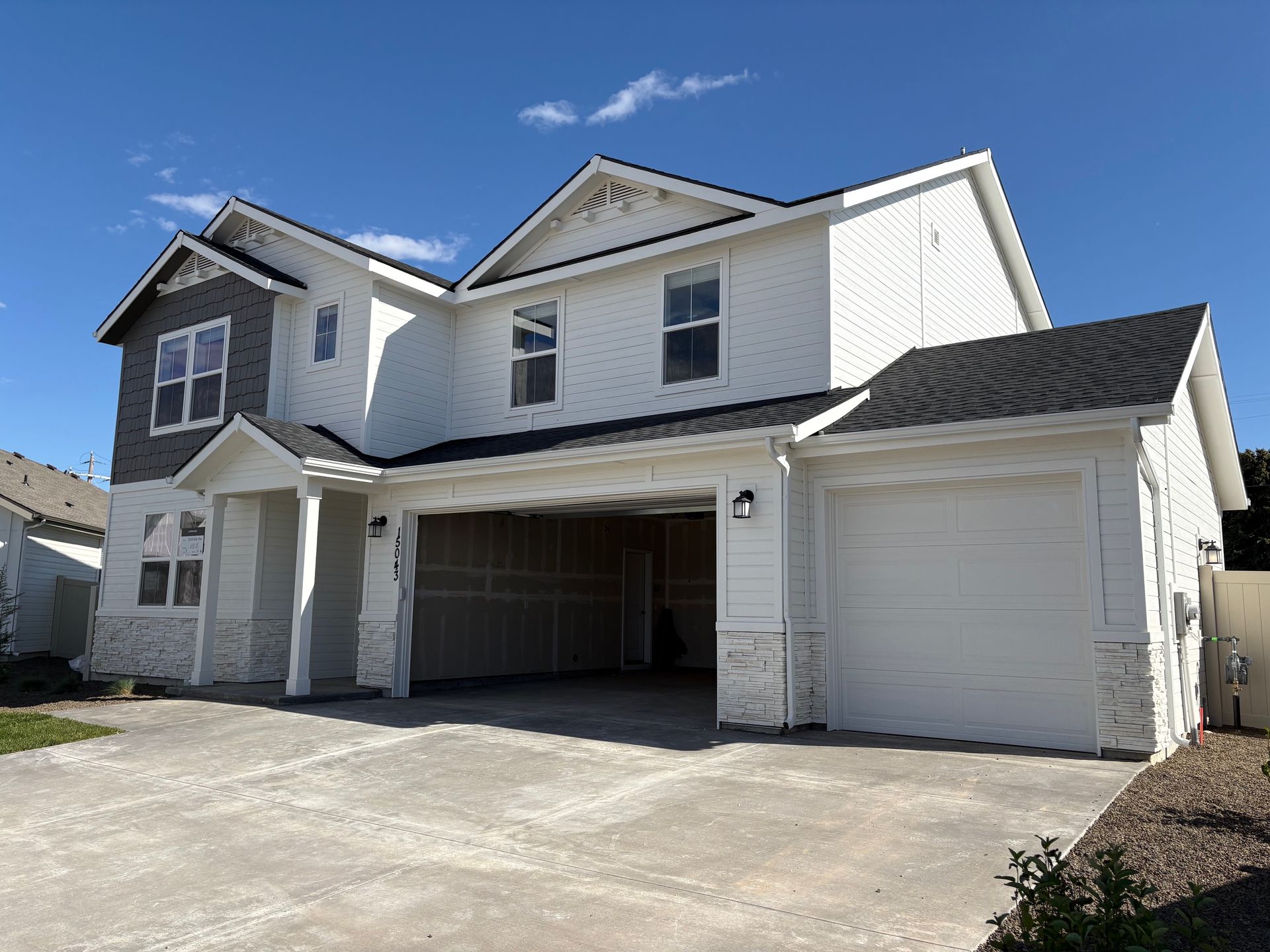 Two-story white house with a two-car garage under a blue sky.