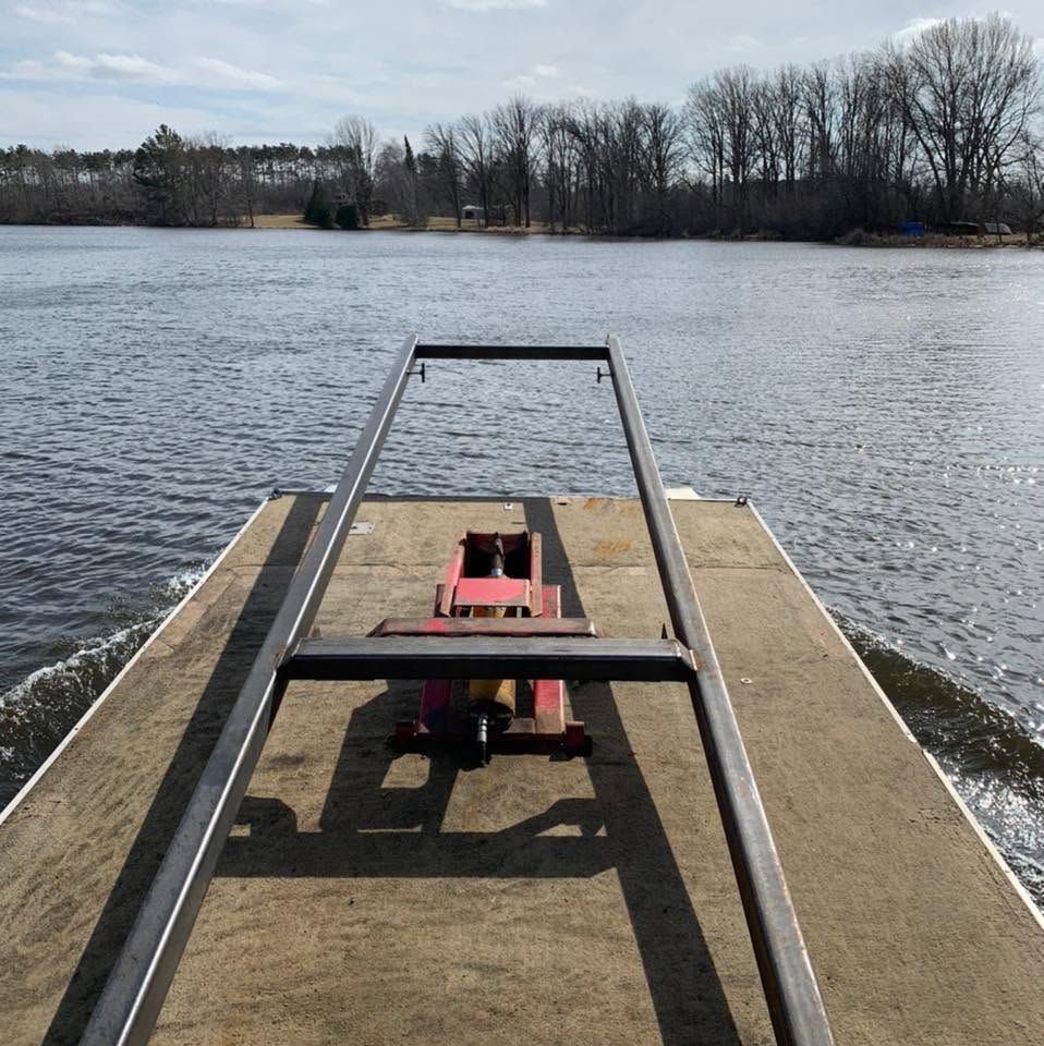 Small red boat or dock cart on a pier, facing a calm lake with bare trees on the far shore