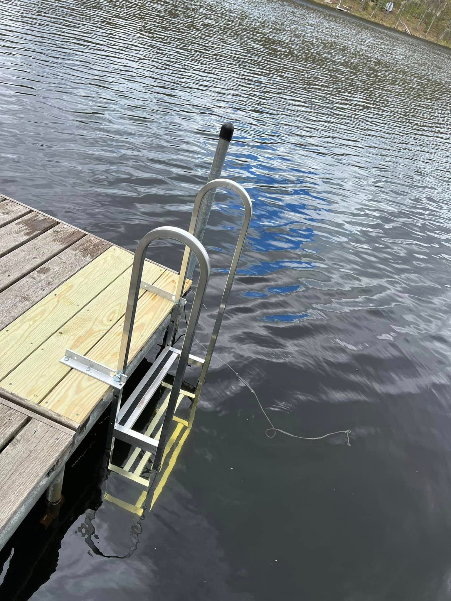 Ladder descending from a wooden dock into rippled water beside a blue kayak and black railing