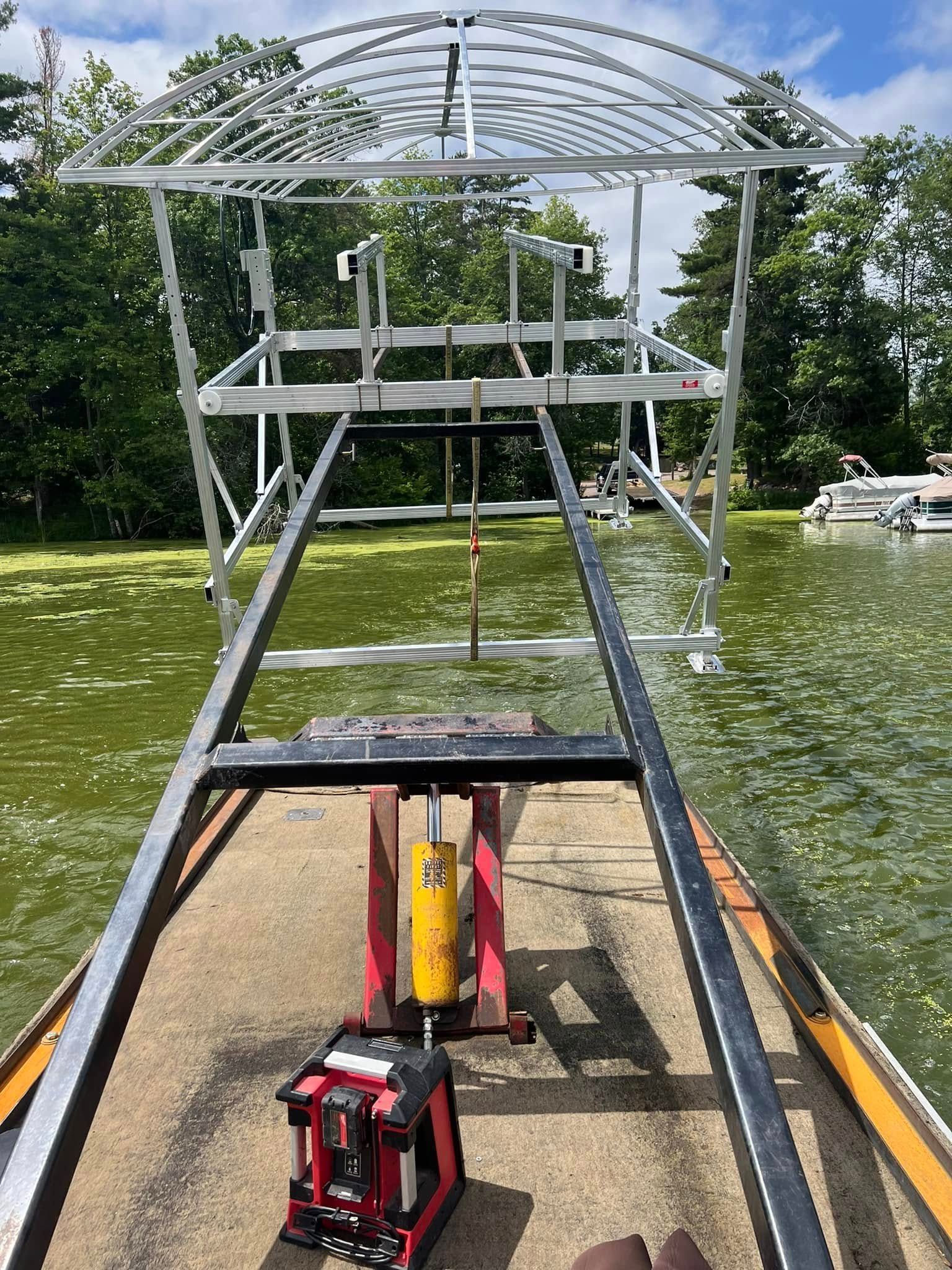 Metal launch ramp on a dock over water, with a red tool in the foreground and trees in the background