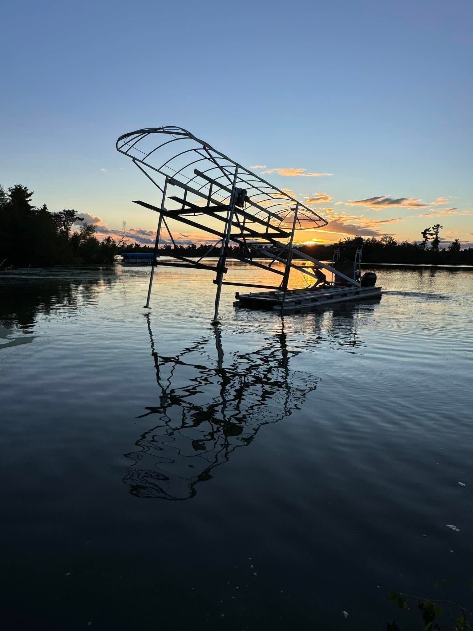Silhouetted dock frame reflected on calm water at sunset under a blue-orange sky