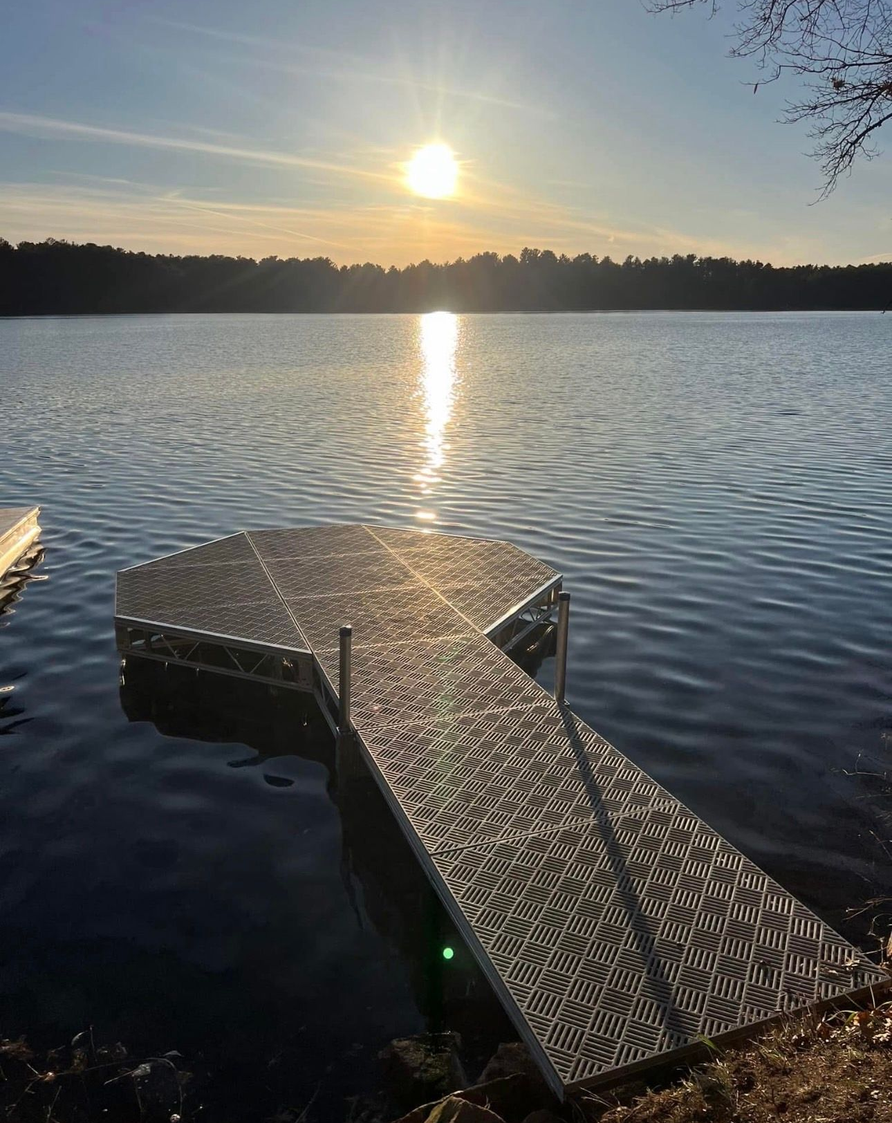 Sunset over a calm lake, with a wooden dock extending into the water