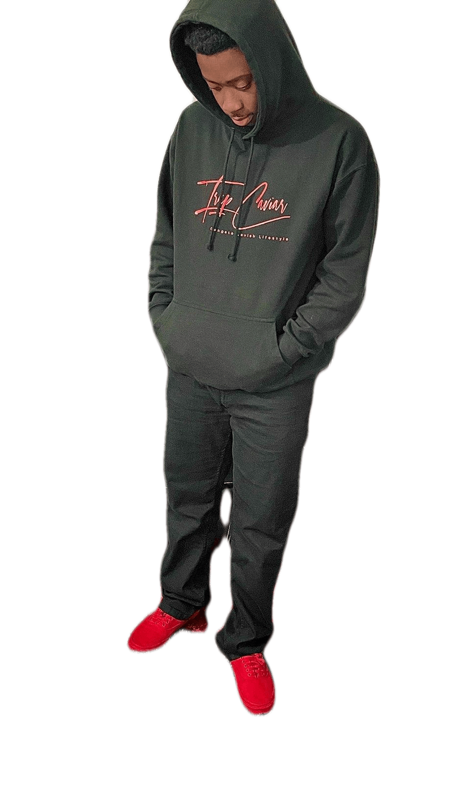 A man wearing a hoodie and red shoes is standing with his hands in his pockets.