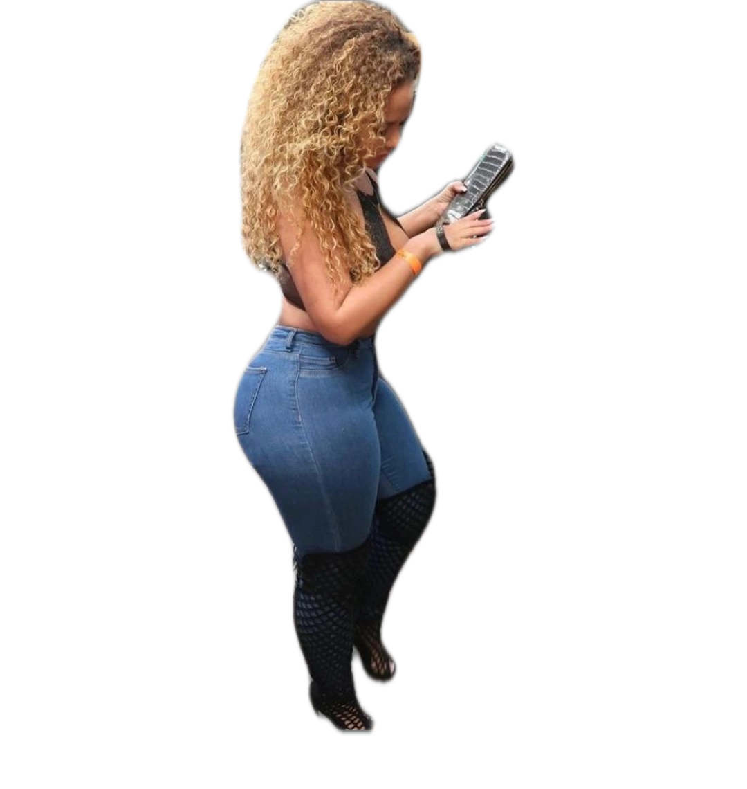 A woman with curly hair is standing and looking at her cell phone.