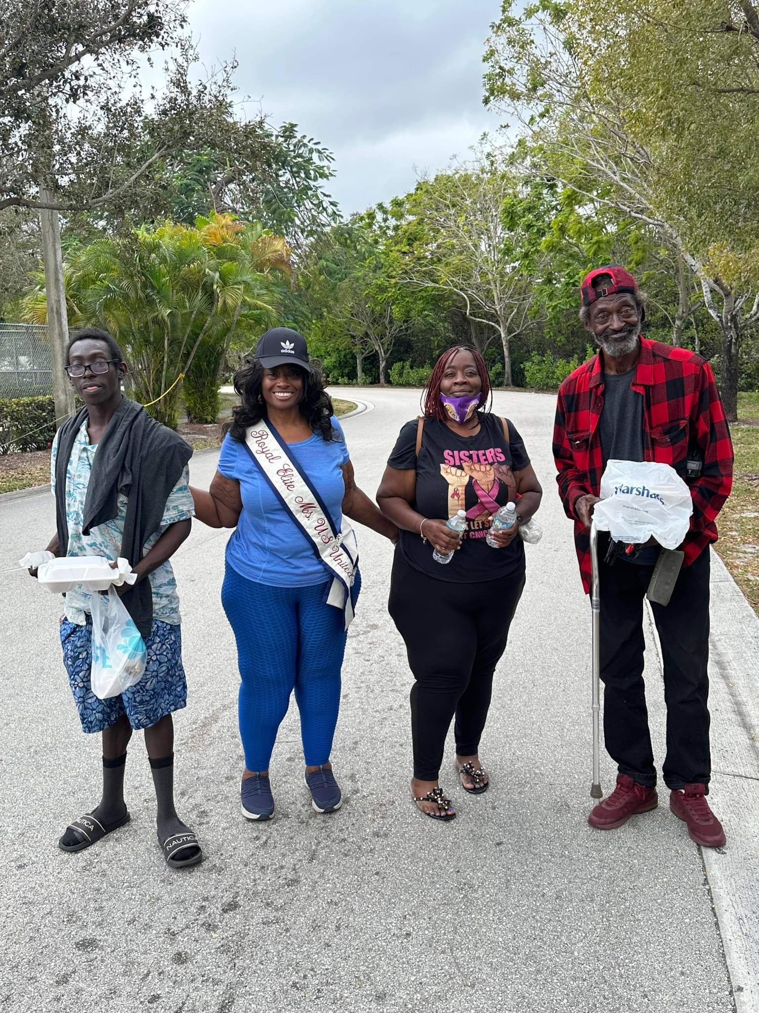 A group of people are standing next to each other on a sidewalk.