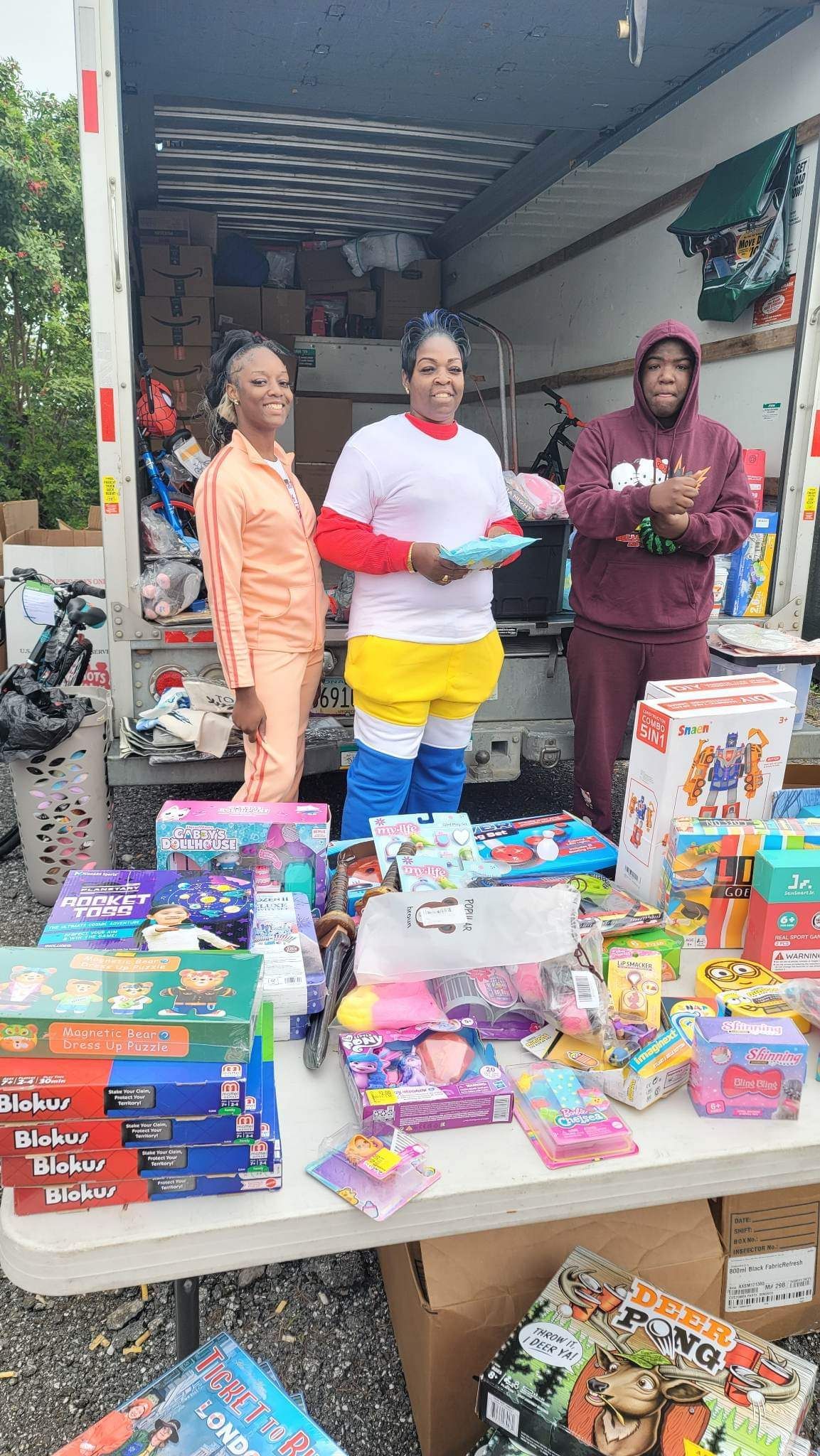 A group of people are standing in front of a truck filled with toys.