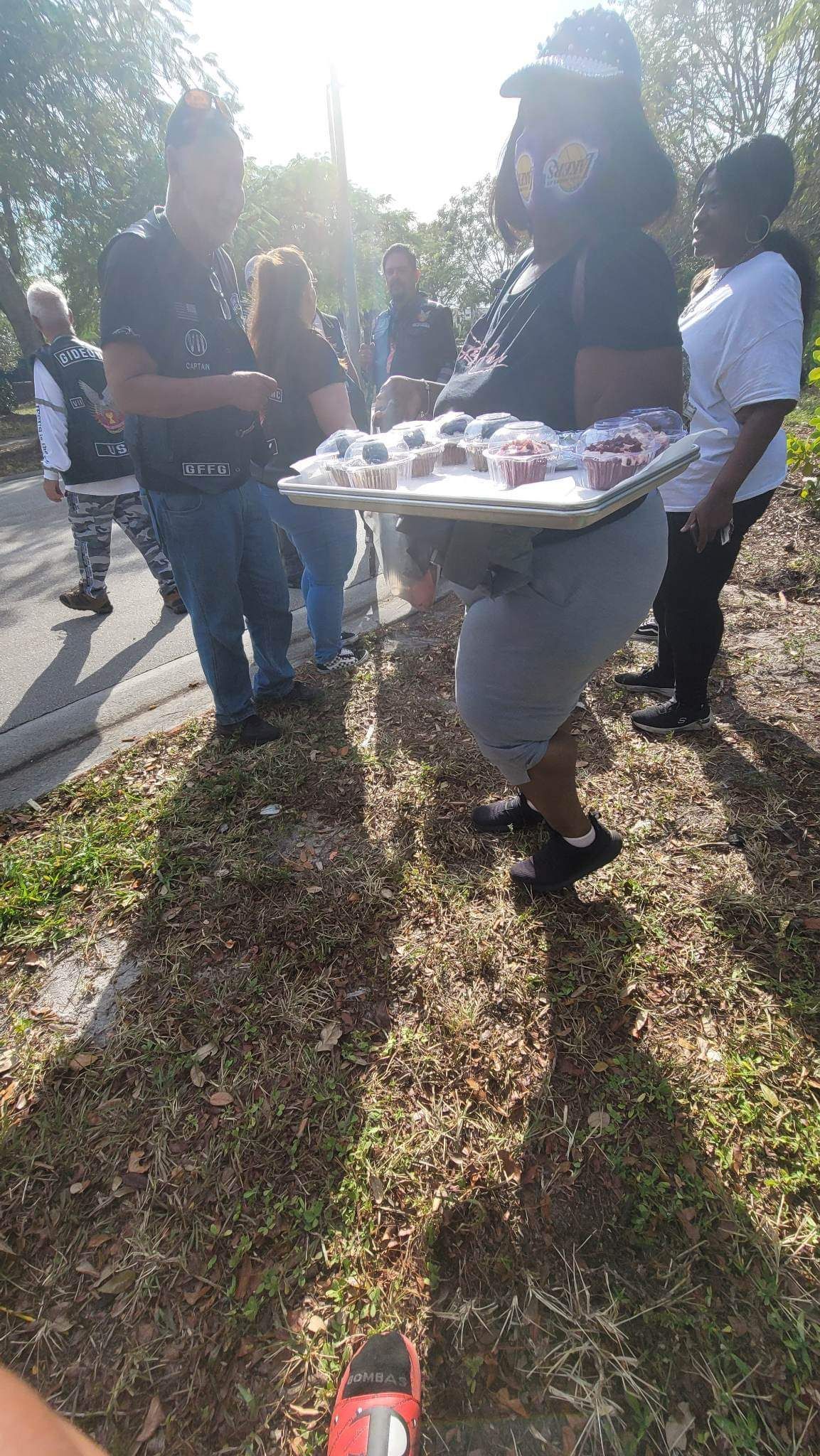 A woman is carrying a tray of food to a group of people.