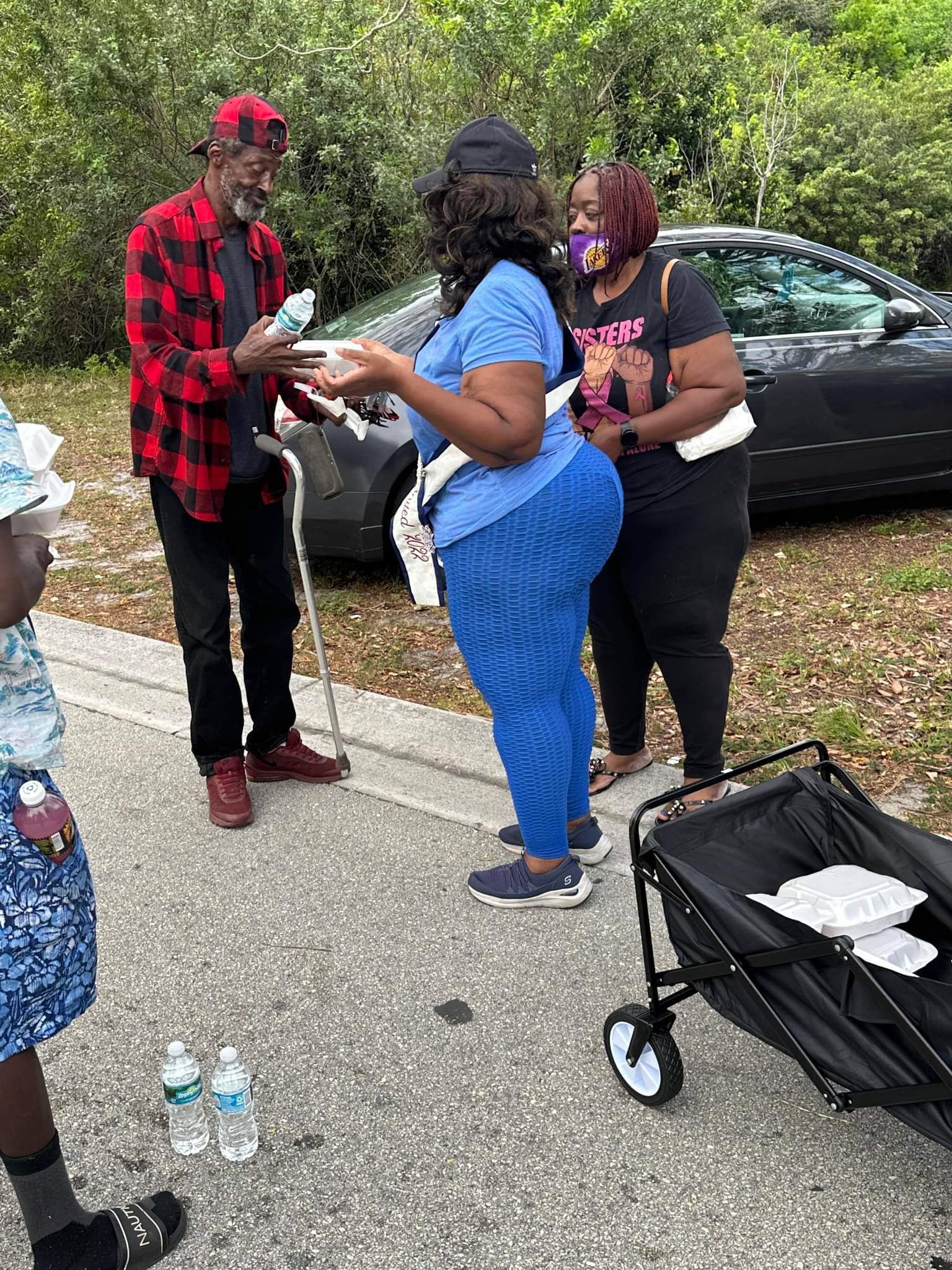 A group of people are standing next to each other on the side of the road.
