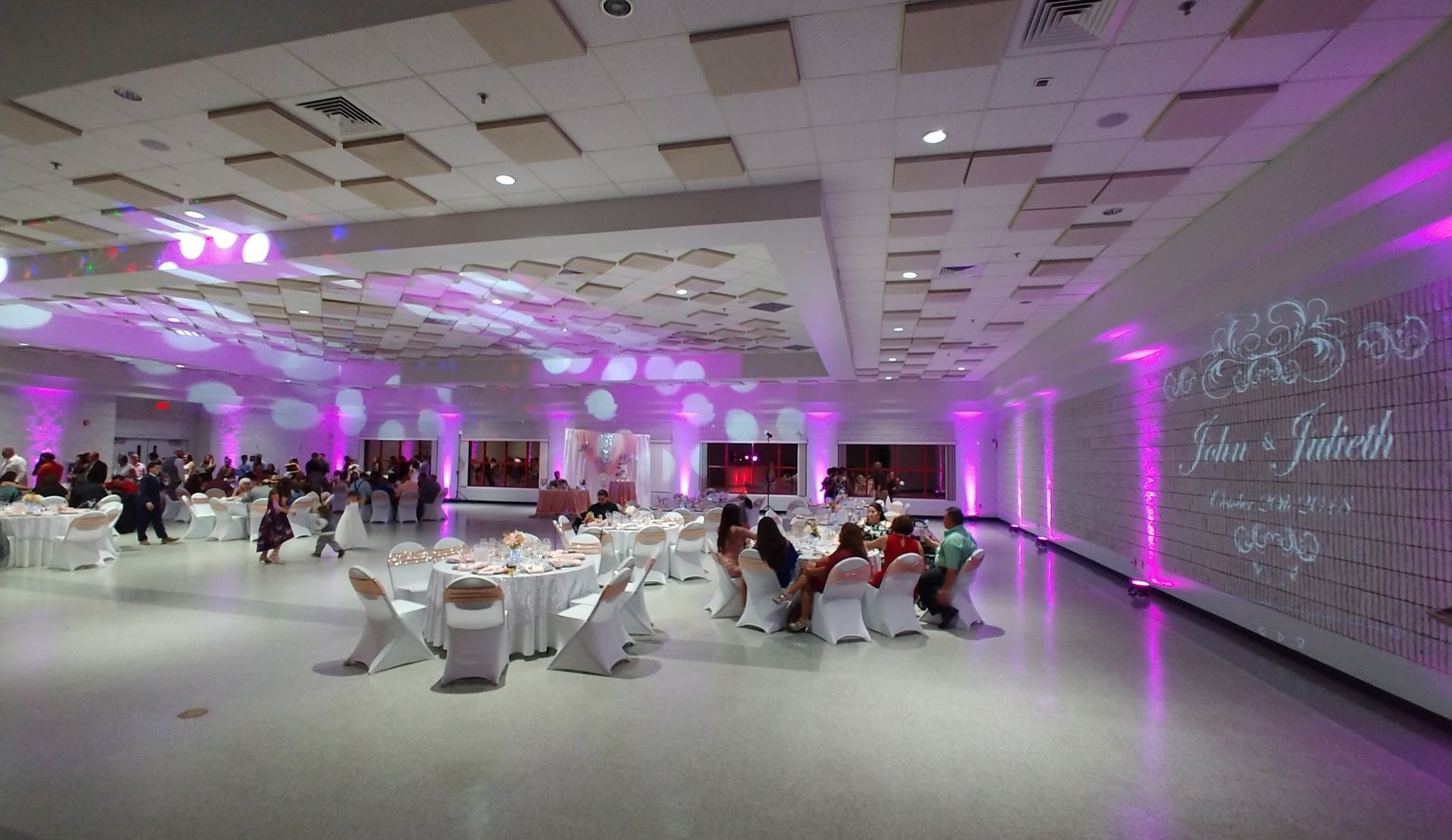 Purple-lit banquet hall with seated guests and decorated tables during an event