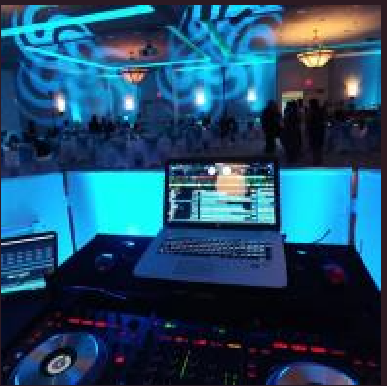 DJ booth with laptop and mixer facing a blue-lit dance floor and crowd in a club
