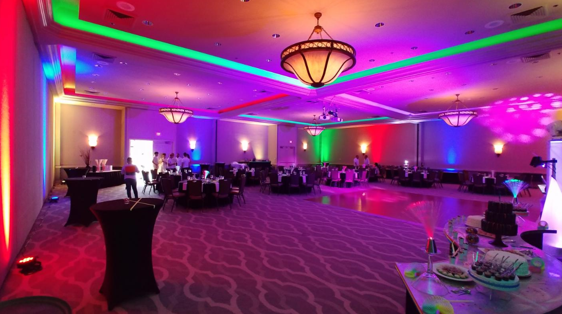 Elegant banquet hall with purple and red lighting, round tables, and a chandelier ceiling.