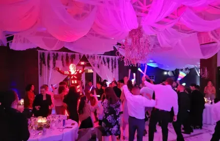 People dancing under pink-lit draped ceiling at a lively indoor party